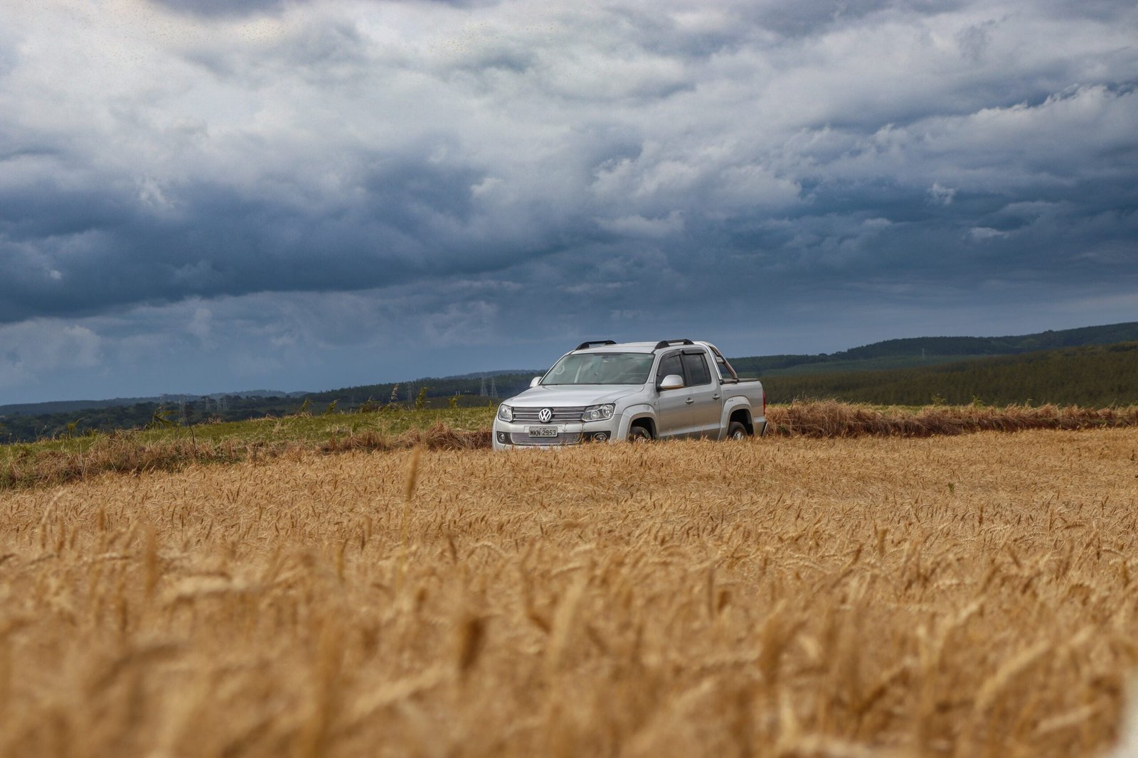 a van parked in a field of wheat under a cloudy sky